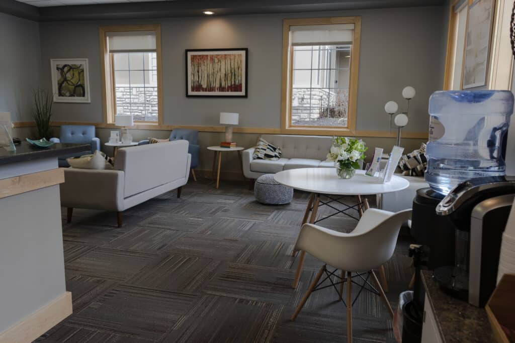 A room with a table, chairs, and a refrigerator for IVF treatment.