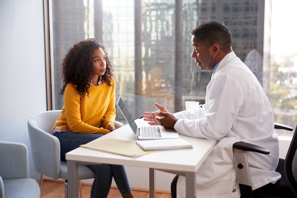 A doctor discussing fertility treatment options with a woman at a desk.
