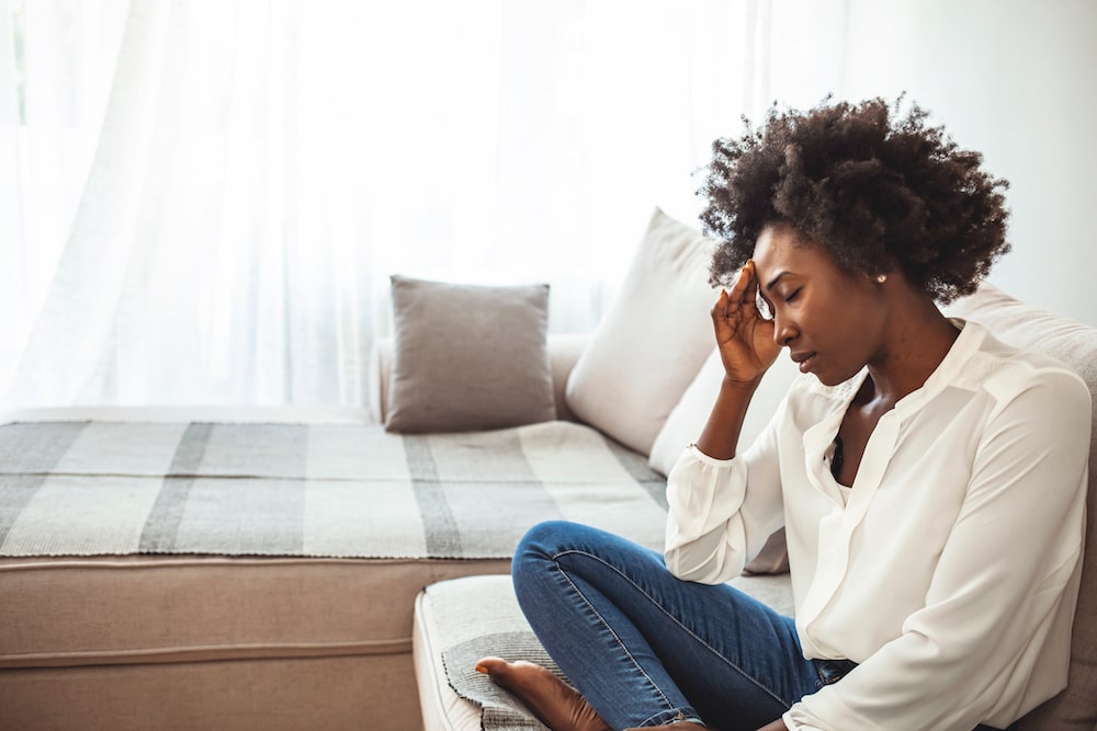 A black woman sitting on a couch, possibly contemplating family planning or fertility treatment options.