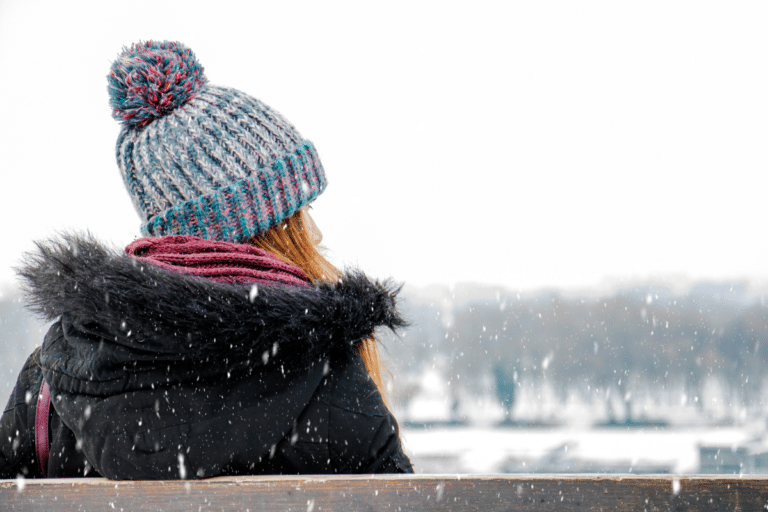 woman in a hat on a bench in the snow