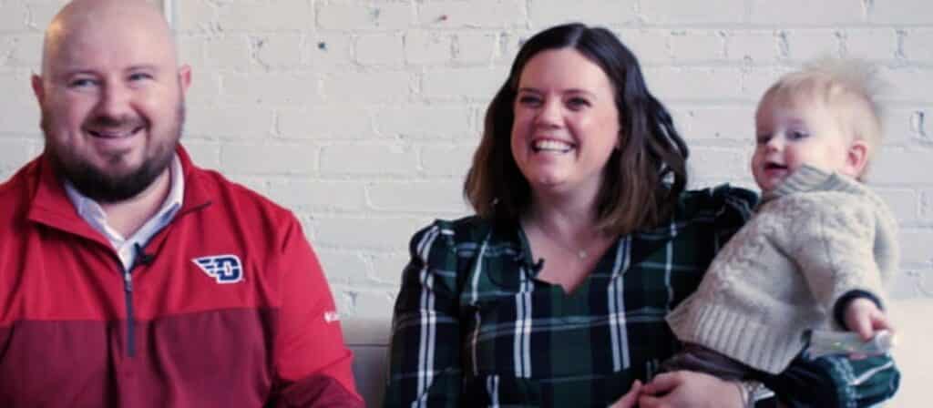 A couple practicing family planning hold their baby in their arms on a cozy couch.