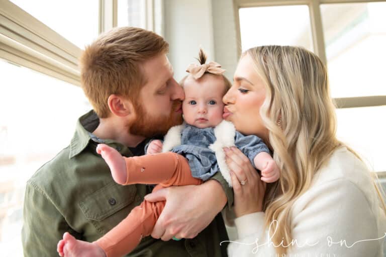 A couple embracing their baby in front of a window, celebrating the joy brought by successful IVF treatment.