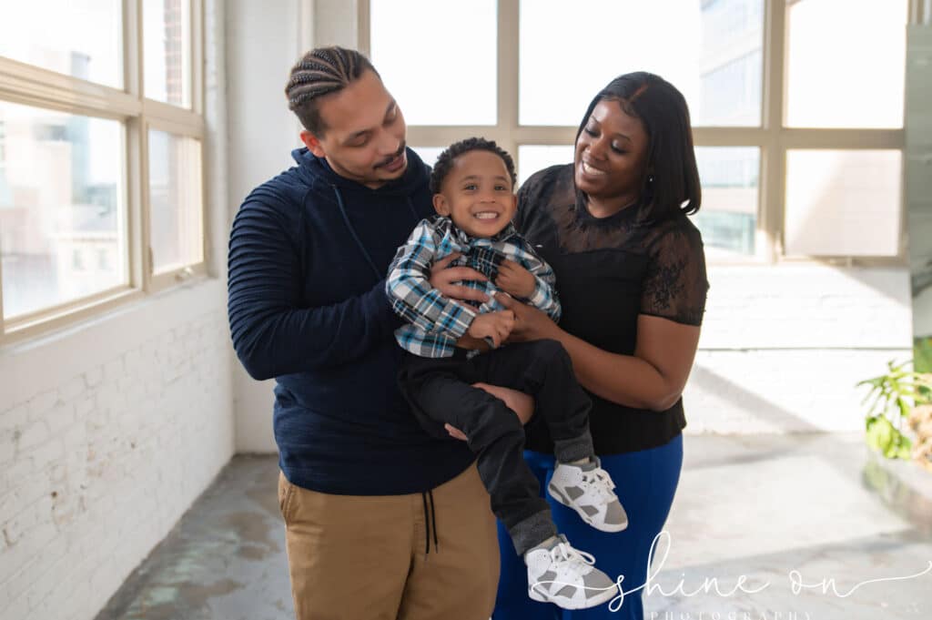 A couple is holding their newborn son in an open space, celebrating the result of successful fertility treatment.