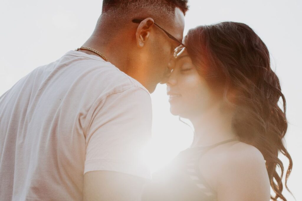 A couple kissing in front of the sunset.