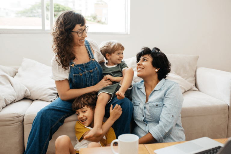 two women with their two kids smiling on the couch