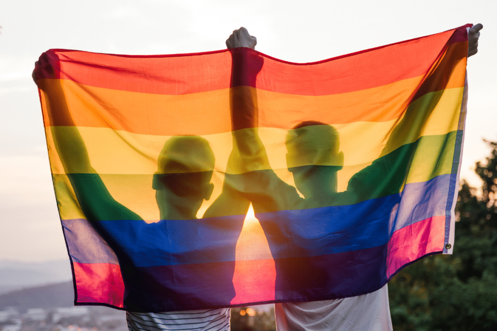 two people holding up a LGBTQIA+ flag for PRIDE month