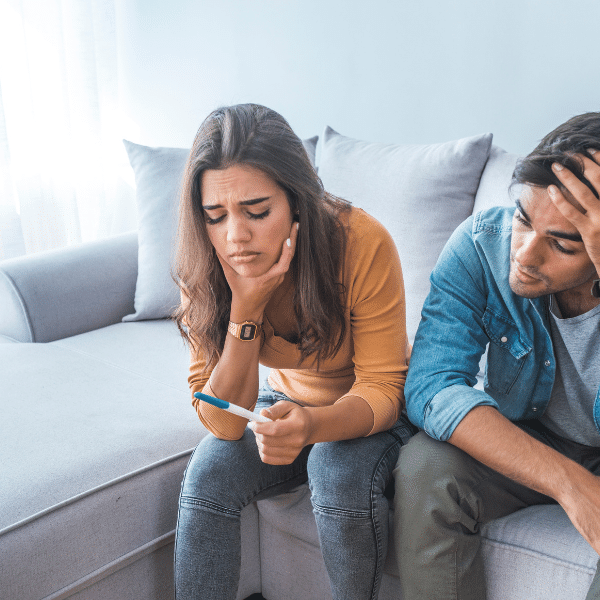 A couple sitting on a couch, engrossed in their phone as they research fertility treatment options like IVF.