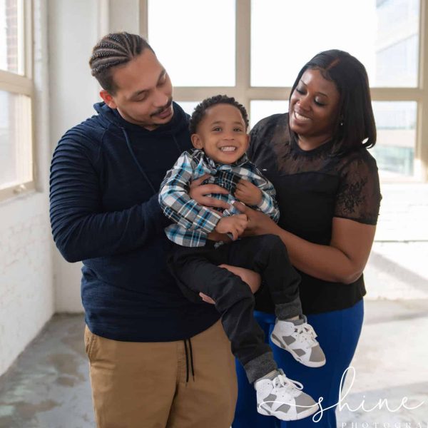 A couple is holding their newborn son in an open space, celebrating the result of successful fertility treatment.