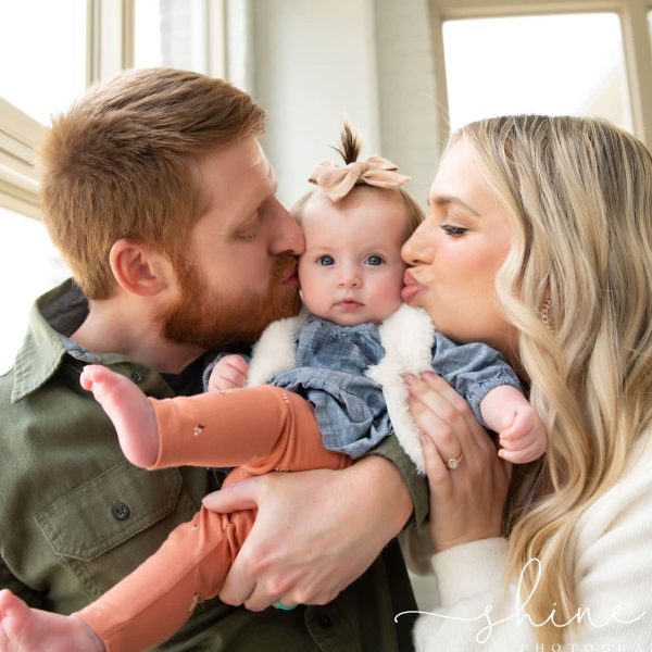 A couple embracing their baby in front of a window, celebrating the joy brought by successful IVF treatment.