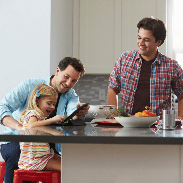 Three men and a girl in a kitchen looking at a tablet while discussing family planning.