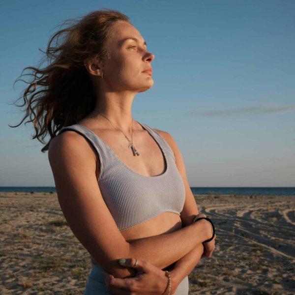 Woman standing on a beach, facing the sun, considering fertility preservation before cancer treatment