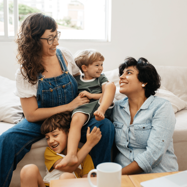 two women with their two kids smiling on the couch