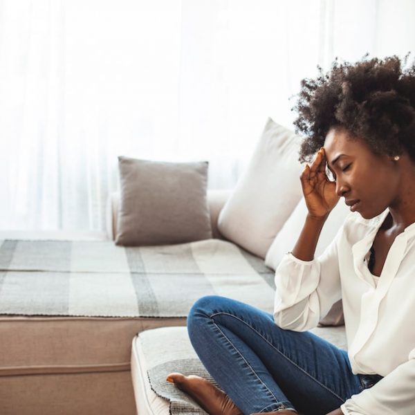 A black woman sitting on a couch, possibly contemplating family planning or fertility treatment options.